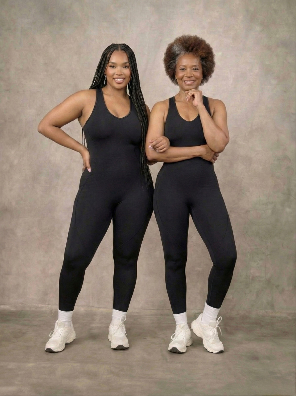 Two women wearing black athletic outfits posing against a gray background